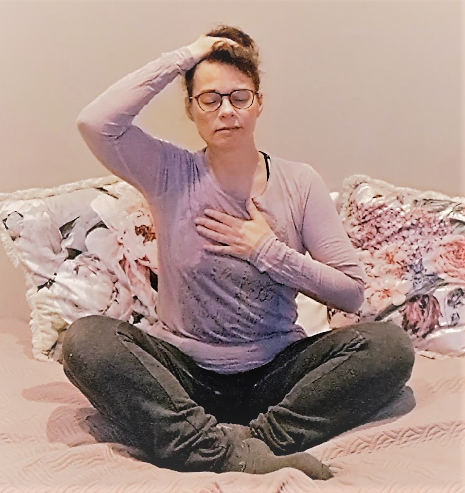 Tmi Resonoiva Ääni, Satu Haapala: nainen risti-istunnassa, käsi pään päällä, toinen käsi rinnan päällä, silmät kiinni