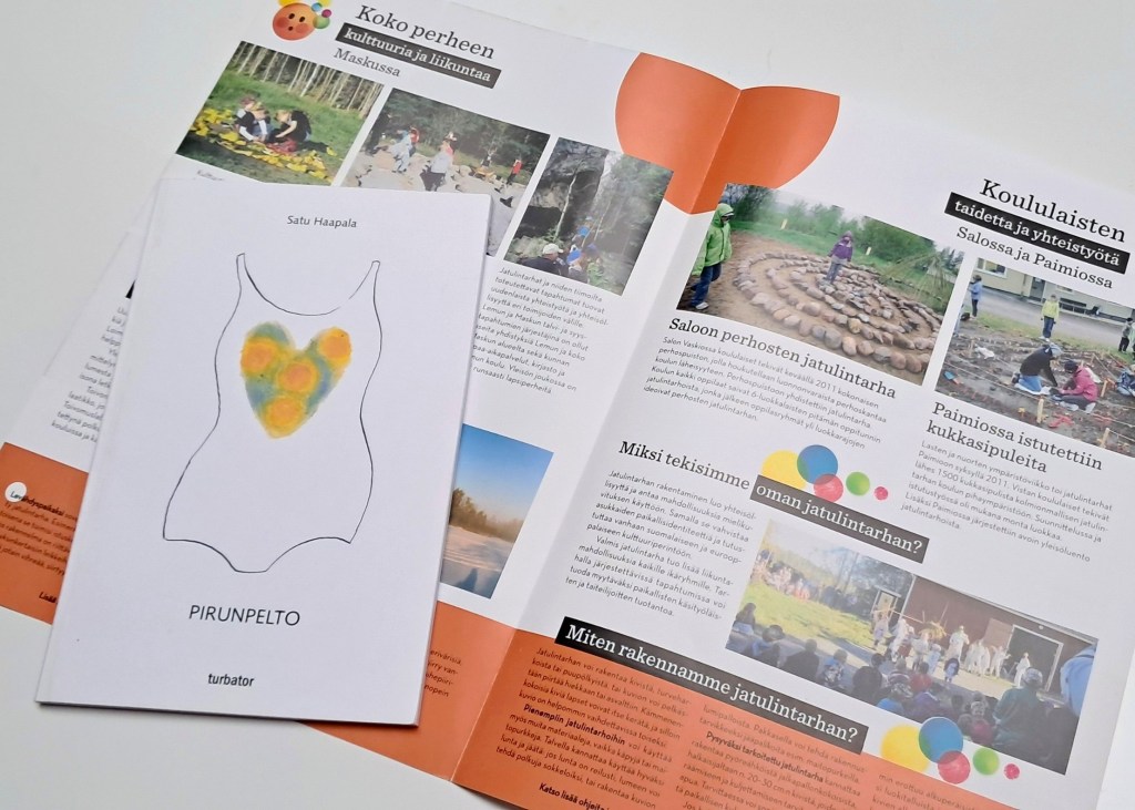 kirjan kannessa teksti "Pirunpelto", taustalla esite jossa tekstejä ja kuvia jatulintarhoista