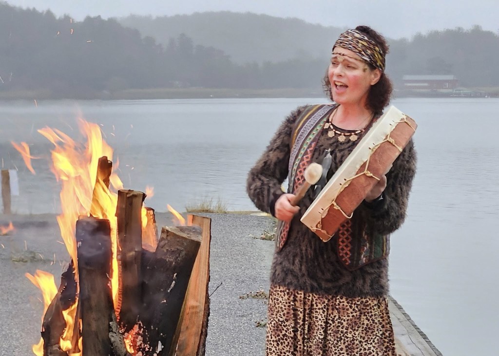 nuotiotuli ja shamaanilaulaja laulamassa rumpu kädessäänj