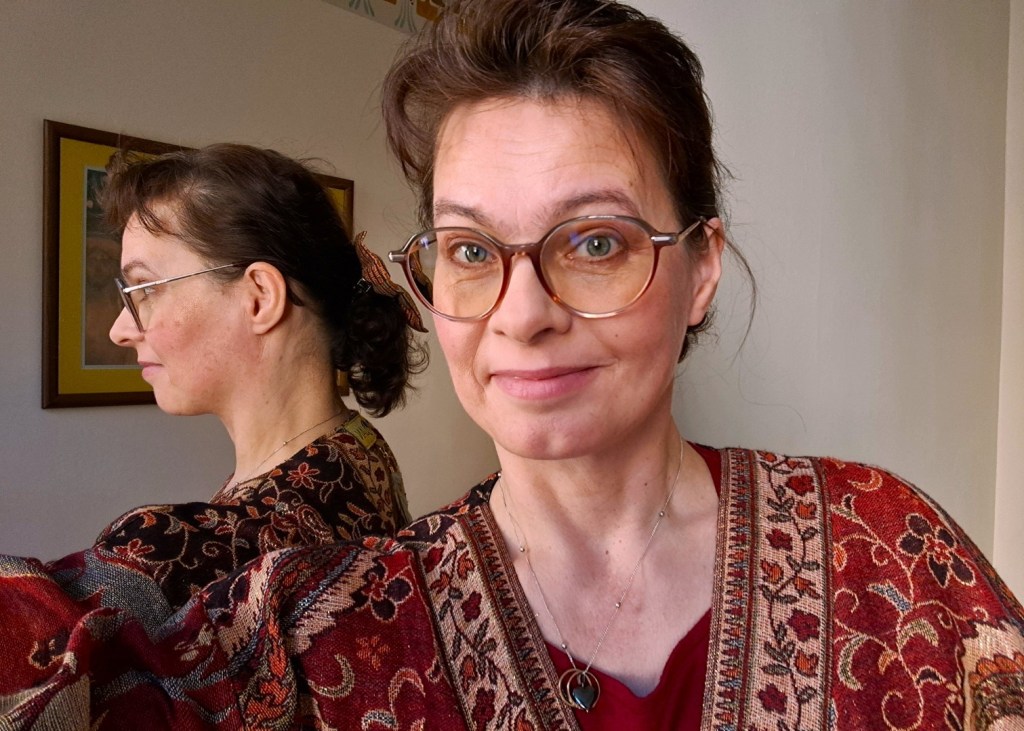 Satu Haapala. henkilö katsoo kameraan, takana peilikuva.